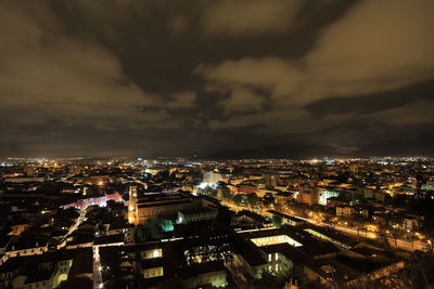 Aerial view of illuminated cityscape against storm clouds