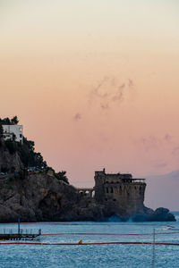 Building by sea against sky during sunset