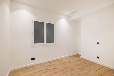 Empty clean room after renovation with white walls, window and wooden floor