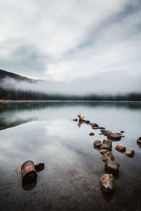 View of stones in lake against sky