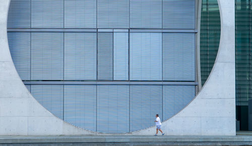Man walking by modern building on sidewalk