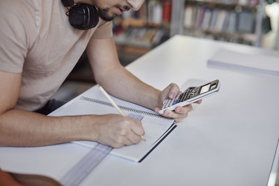 Male student making calculations with calculator