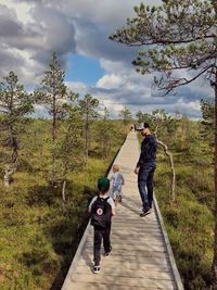 Rear view of man and woman standing by trees against sky