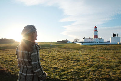 Woman standing on grassy field against sky
