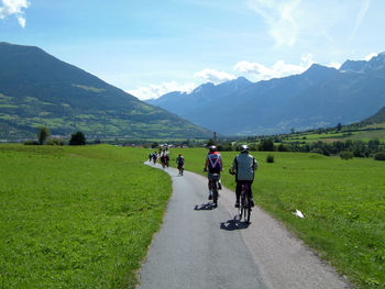 Rear view of people riding bicycle on road