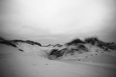 Scenic view of sand dunes on beach against sky 