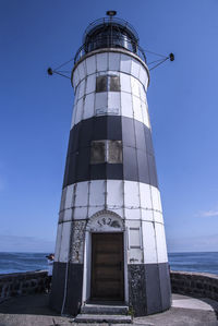 Low angle view of lighthouse by sea against sky