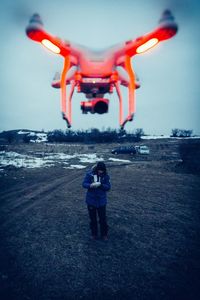 Rear view of woman with airplane flying in sky