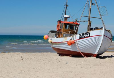 Ship moored on beach against clear sky