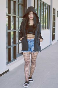 Portrait of beautiful young woman standing against wall