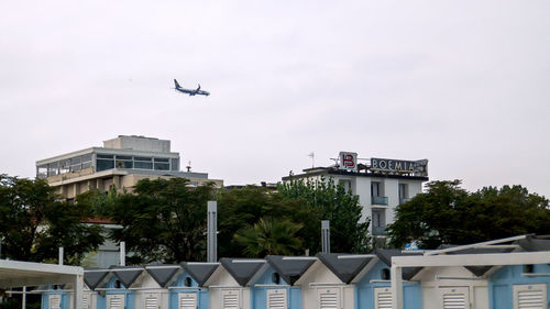 Low angle view of airplane flying over building against sky