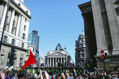 People in front of buildings against sky in city