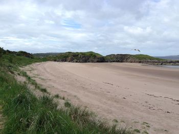 View of calm beach against cloudy sky