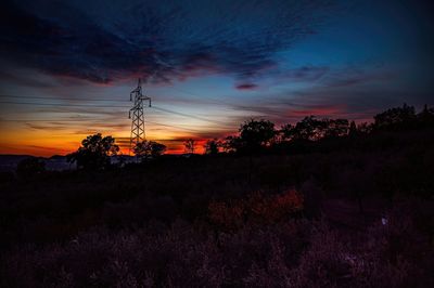 Silhouette trees on field against romantic sky at sunset