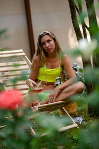 Portrait of young woman sitting on field on a garden chair