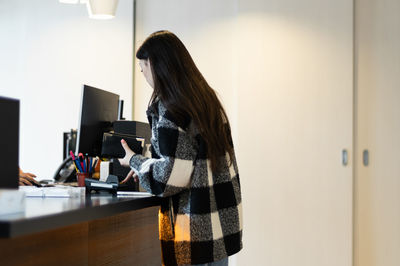 A young girl pays at the counter at the hospital reception.