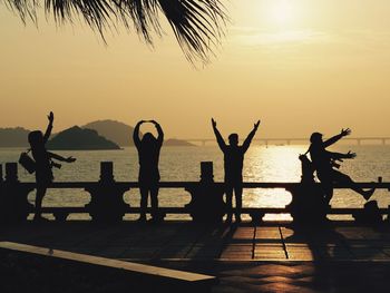 Silhouette people at beach against sky during sunset