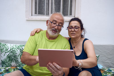 Young man using smart phone while sitting on laptop