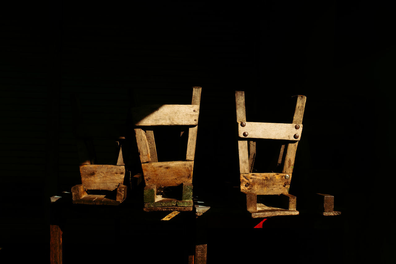 CLOSE-UP OF WOODEN STRUCTURE AGAINST DARK BACKGROUND