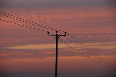 Low angle view of silhouette electricity pylon against romantic sky