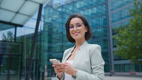 Young woman using mobile phone while standing in city
