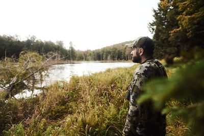 Portrait of young man standing by lake