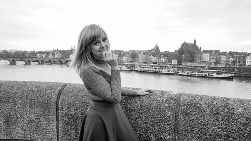 Portrait of smiling woman standing by river against sky