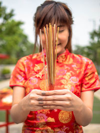 Midsection of woman holding red while standing against blurred background