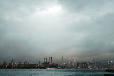 Sea by buildings against sky in city