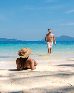 Rear view of woman standing at beach against sky