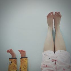 Low section of woman and baby with feet on wall at home