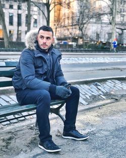 Portrait of man sitting on street in winter