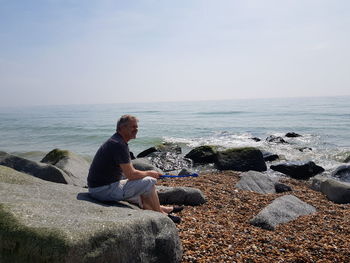 Man sitting on rock at beach