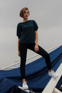 Portrait of young woman standing on built structure against sky