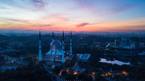 High angle view of mosque amidst city at sunset