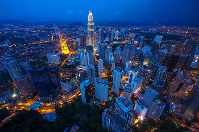 Aerial view of modern cityscape against blue sky at night