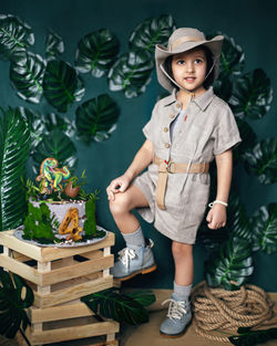 Child dressed in the style of a jungle treasure hunter with a hat and a dinosaur cake