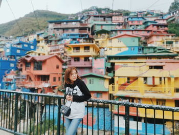 Woman standing on railing against buildings in city