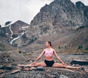 Full length of woman exercising against rocky mountain