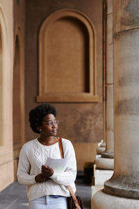 Full length of woman sitting outside building