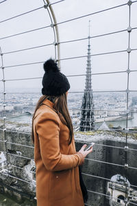 Woman standing by river in city against clear sky during winter