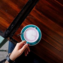 Directly above shot of hand holding coffee cup on table