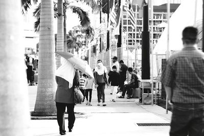 Rear view of people walking on street in city