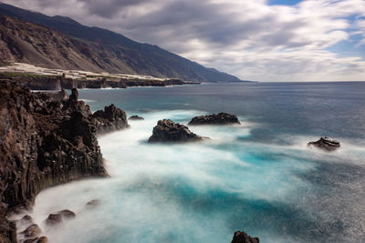 Scenic view of sea and mountains against sky