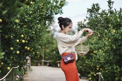 Portrait of young woman standing against trees