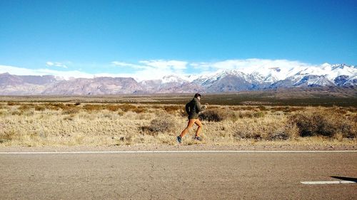 Man walking on road against mountain range