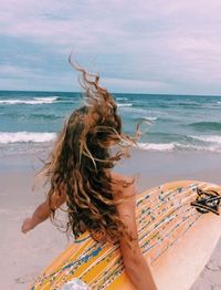 Midsection of woman on beach against sky