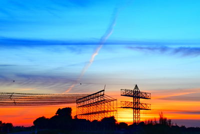 Low angle view of silhouette cranes against sky during sunset