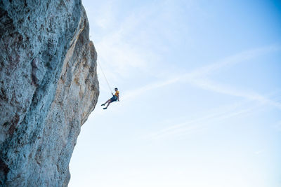 Low angle view of person on rock against sky