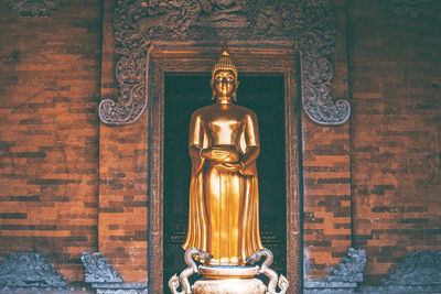 Statue of buddha against wall of building